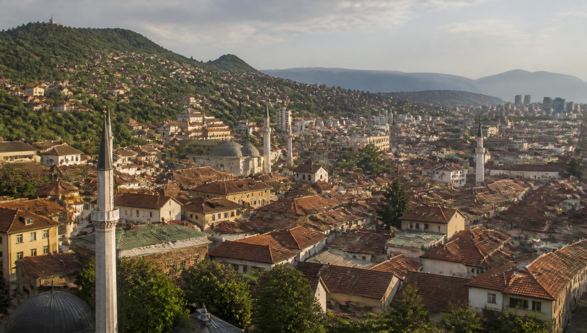 Sarajevo old town rooftops and minarets in the valley below forested hills